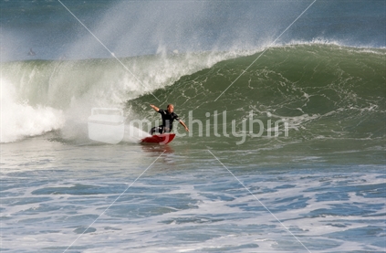 Surfer doing a bottom turn on a wave at Rocky Point, Taranaki