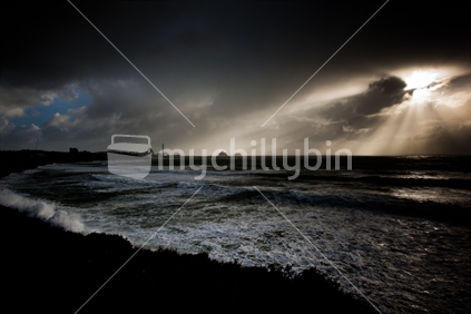 Rays of sun breaking through storm clouds along the New Plymouth coastline, New Zealand.