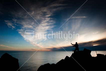 A fisherman casts out to sea in front of a sunrise cloud formation.