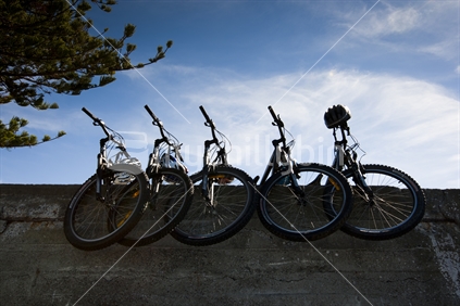 5 push bikes stacked up on a wall, at Kaikoura beach. New Zealand. 