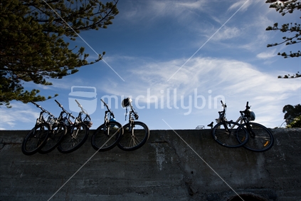 7 push bikes stacked up on a wall, at Kaikoura beach. New Zealand. 