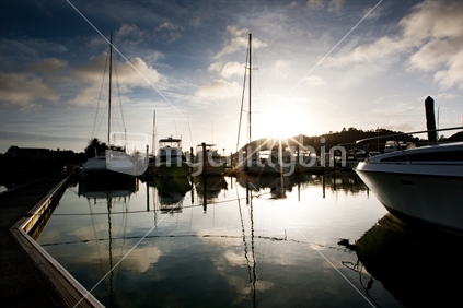Sun rising behind yachts & fishing boats moored at Whitianga Marina, Coromandel, New Zealand.