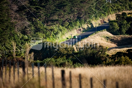 A car traveling along a road passing through rural Taranaki, New Zealand.