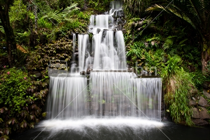 A waterfall flowing into a pond in lush bush in Pukekura Park, Taranaki.