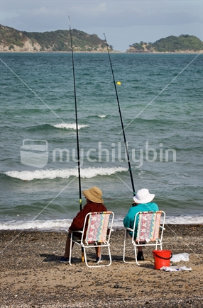 Two elderly ladies fishing from their fold up chairs