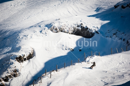A snowboarder riding down a snow covered Manganui skifield, Mt Taranaki / Egmont.