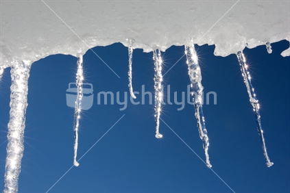 Sun shining through icicles hanging off a hut at Whakapapa, Mt Ruapehu