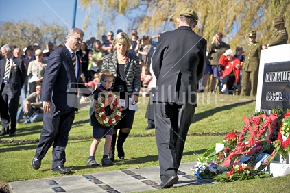 Clayton Cosgrove M.P. assisting young man with wreath on ANZAC day.