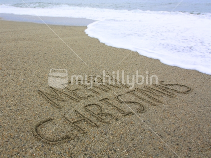 Merry Christmas written in the sand
