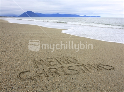 Merry Christmas written in the sand