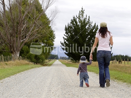Mother and son walking along a gravel country road
