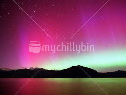 Aurora Australis, southern lights. Rays and green arch reflecting in the waters of Lake Brunner, West Coast, South Island, NZ