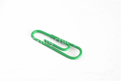 Single green paper clip with room on a white background for your composition crop.