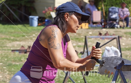 Maori female competitor in the women's single handed wood sawing competition, at the New Zealand woodchopping events. 