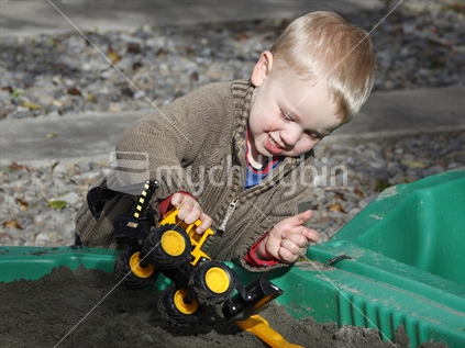 Boy playing with his toys in the sand-pit