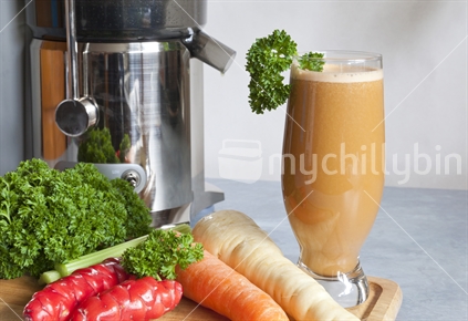 Juicing raw fresh vegetables for good health.
Glass of parsnip,carrot,yam,celery and parsley juice.