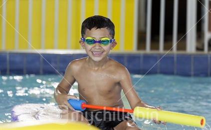 Young boy playing a game with the water pump at an indoor swimming pool.  (Raised ISO image)
