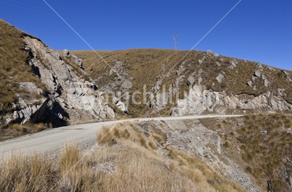 Gravel road through Danseys Pass. A mountain pass located in the Kakanui Mountains between Central Otago and North Otago, South Island, New Zealand.  Old bridge piles made from stone can be seen below the road where there has been a slip.