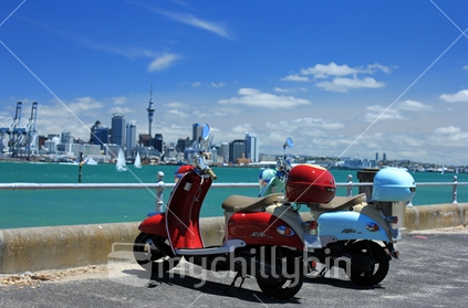 Scooters parked in Devonport with Auckland CBD beyond.