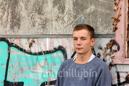 Teenage boy standing by derelict building