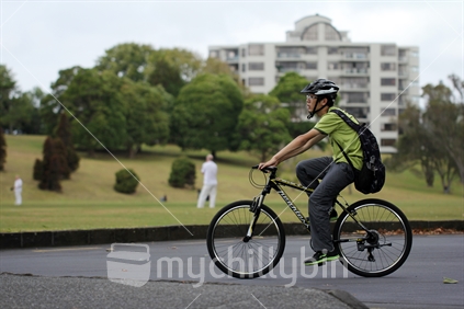 Young asian man on a bike in the Auckland Domain, with blurred background
