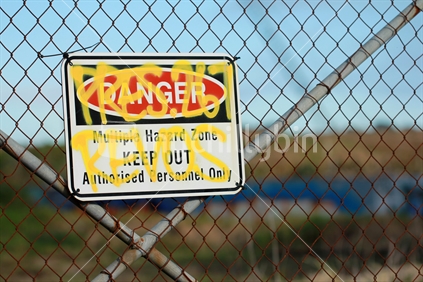 Defaced danger sign on fence