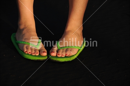 Lime green jandals on black sand, west coast, New Zealand