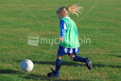 Young blonde girl playing soccer