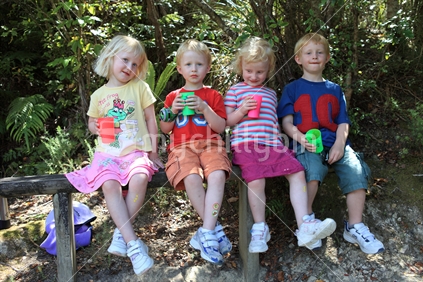 Four children drinking soup on a seat in the bush, New Zealand