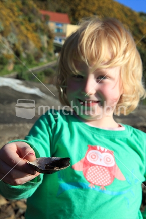 Young girl showing a paua shell with a fish in it