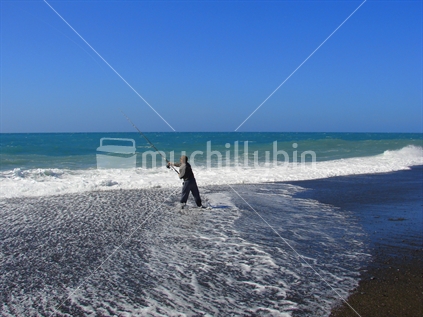 A keen fisherman casting his rod into the ocean