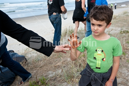 Boy shows his hand with toxic oil from debris on Mount maunganui beach. Many people arrive to see the mess, and beached containers on 13 October, of the ship wrecked on the Astrolabe Reef on 5 October 2011.