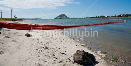 Long orange oil boom at an Otumoetai beach in Tauranga, following the Rena shipping disaster. The boom is inflatable and designed to protect beach from oil contamination.
