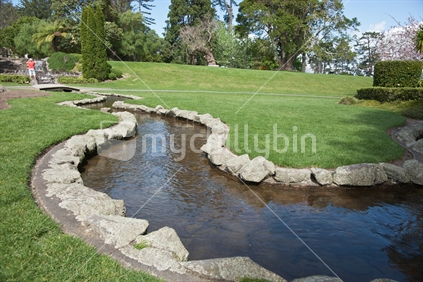Garden stream, with family photo in progress in the background. Yatton Park, Tauranga