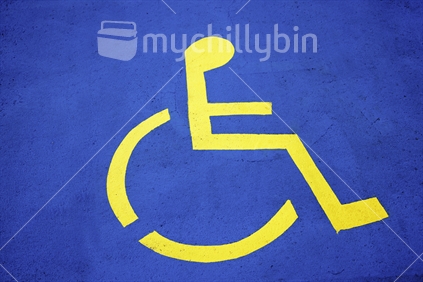 Disabled car park sign in bright blue and yellow on concrete. 