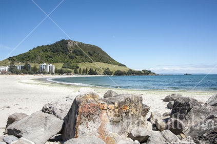 Scenic Mount Maunganui, rocks on beach at Moturiki Island in foreground.