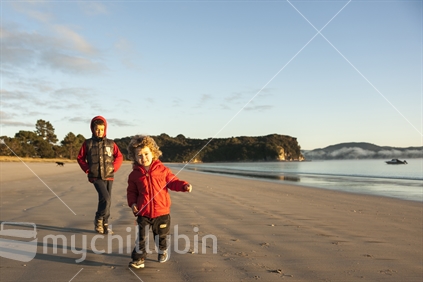 Two small boys play on firm sand at Cooks beach.