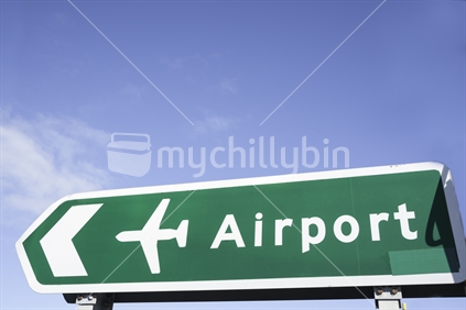 Airport highway direction sign against blue sky.