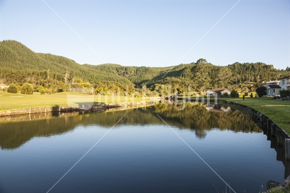 Calm reflective pond surrounded by hills.
