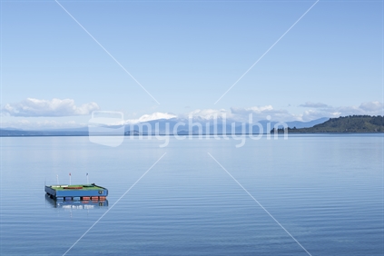 Lake taupo with view to distant snow capped mountains, and golf platform in the foreground.