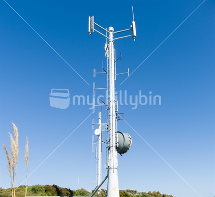 Mobile Communications tower on Bluff Hill, South Island, New Zealand stands against clear blue sky.