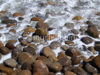 Foamy beach wash over the stones at Maketu
