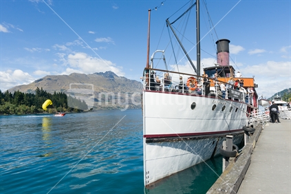 Earnslaw docked at Queenstown's Lake Wakatipu, on 1 March 2015. Passengers on board and ready to leave the dock. The yellow paraglider in the background is synonomous with the adventure tourist offerins the town is renown for.