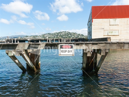 Danger sign on old pier warning to keep off