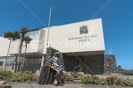 Statue of John Ballance outside Whanganui District Council building given a crochet multi-colour rug and some other aditions.