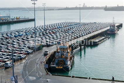 Auckland, 22 May 2016; Rows and rows of newly imported second hand cars parked on Auckland wharf waiting for inspection and delivery with silhouette of ship backlit