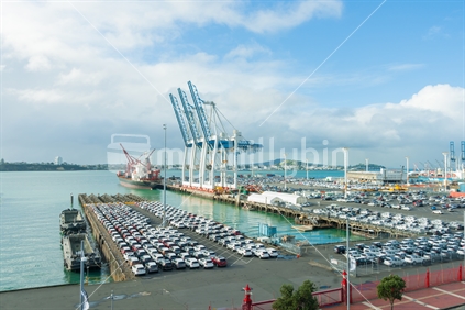 Looking down on Quay Street, Port of Auckland car import wharf and large cranes on next wharf pier, Mount Victoria and North Head