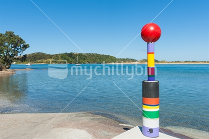 Colourful modern sculpture positioned on edge of boat ramp and scenic estuary Ngunguru