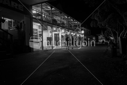 Russell , Bay of Islands at night The Strand with tourists in night light wandering in front of colonial style buildings in monochrome.