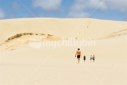 Young people climb Te Paki Sand Dunes, enormous white dunes a favorite tourist attraction and fun place Northland, New Zealand
